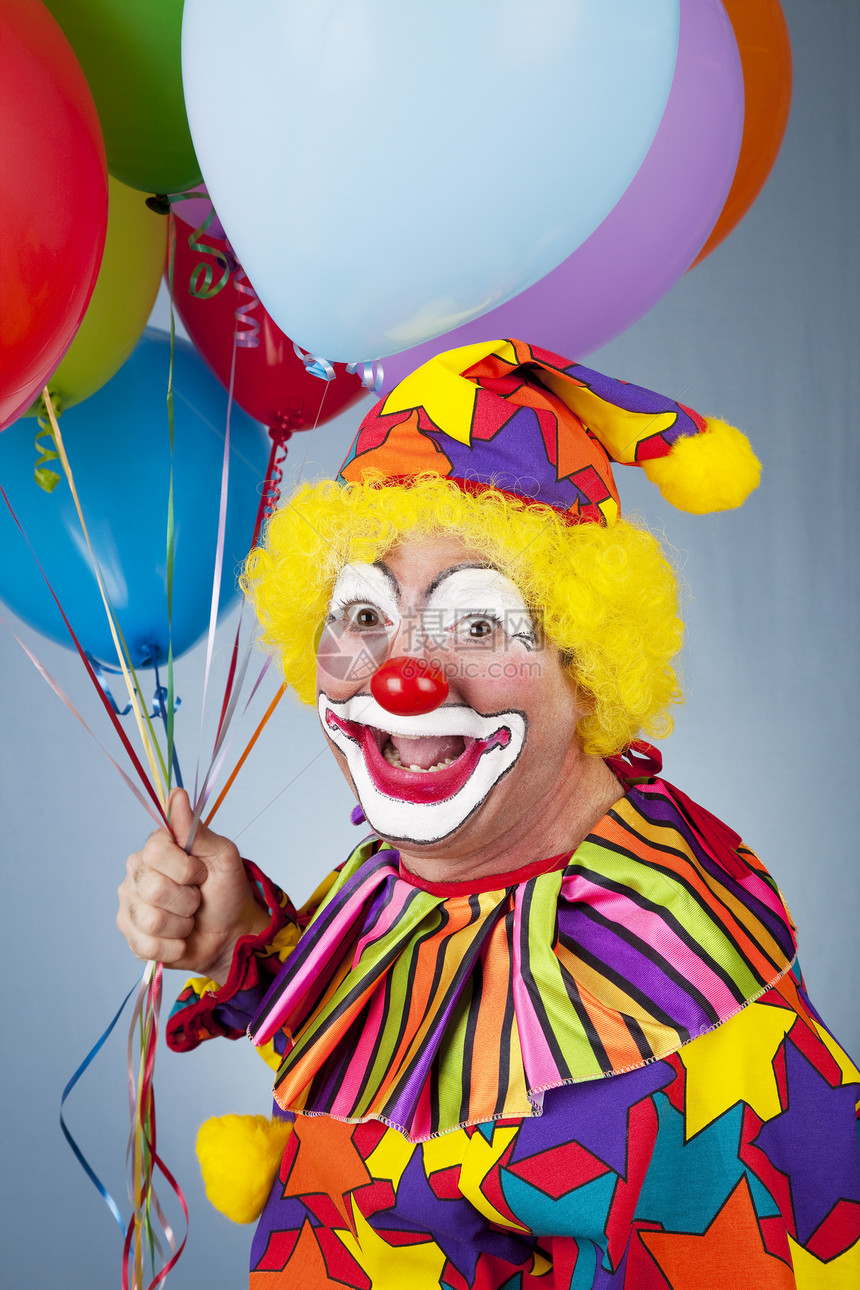 快乐小丑的肖像拿着一束气球图片
