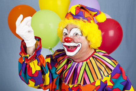欢乐的小丑在喜庆气球背景前抓起他的手指图片