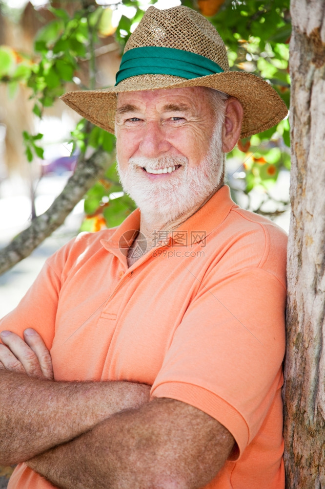 一个英俊的高级男子肖像穿着巴拿马的帽子靠在树上图片