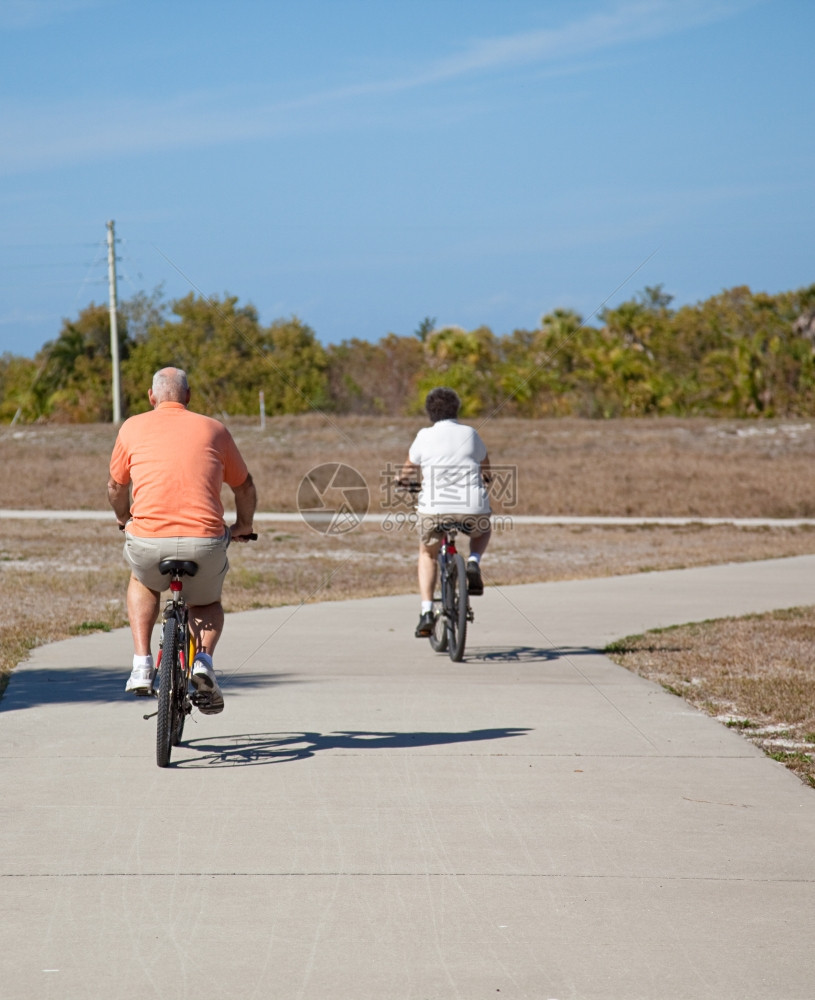 一对老年夫妇骑自行车的近视关注丈夫在前景中图片