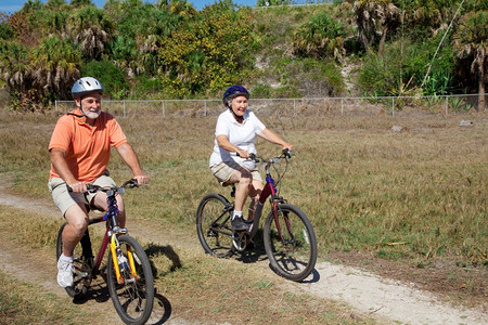 快乐的老年夫妇骑自行车穿过公园图片