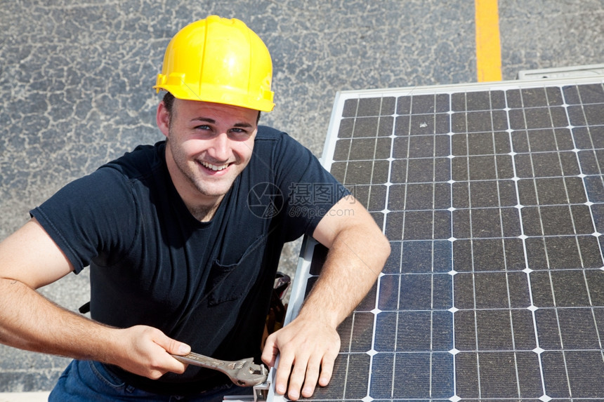 英俊的年轻电工在大楼旁边安装太阳能电池板时微笑着容图片