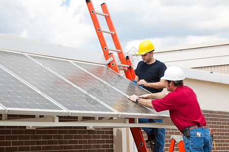 工人在建筑物屋顶上安装节能太阳电池板高清图片