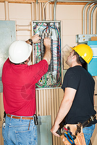 电工和学徒在业面板上换出一个故障断路器图片