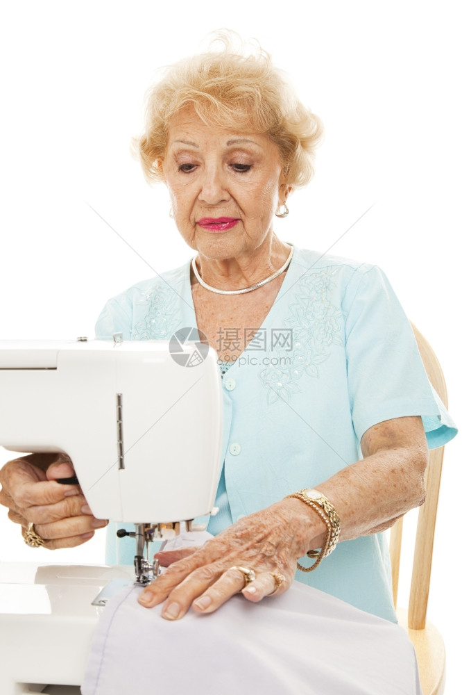 退休的老年妇女缝纫窗帘白的孤立无援图片