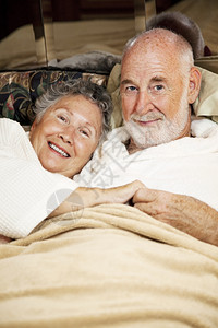 幸福的老夫妇在床上缠着垂直的视野图片