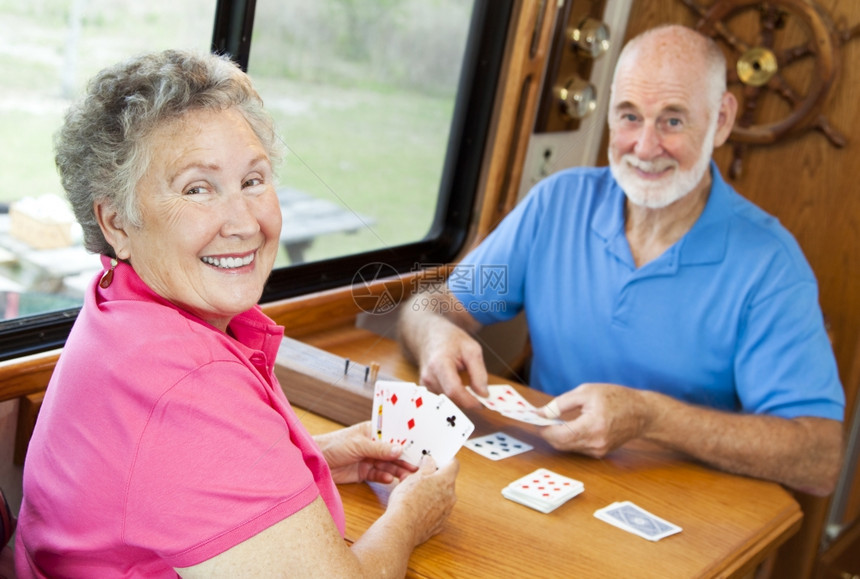 快乐的退休夫妇玩牌在他们的汽车家里图片