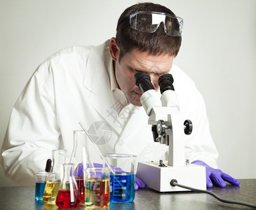 研究化学品和实验室显微镜的科学家图片