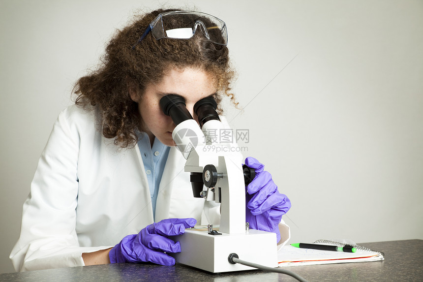 大学生或高中通过显微镜观察并作笔记图片
