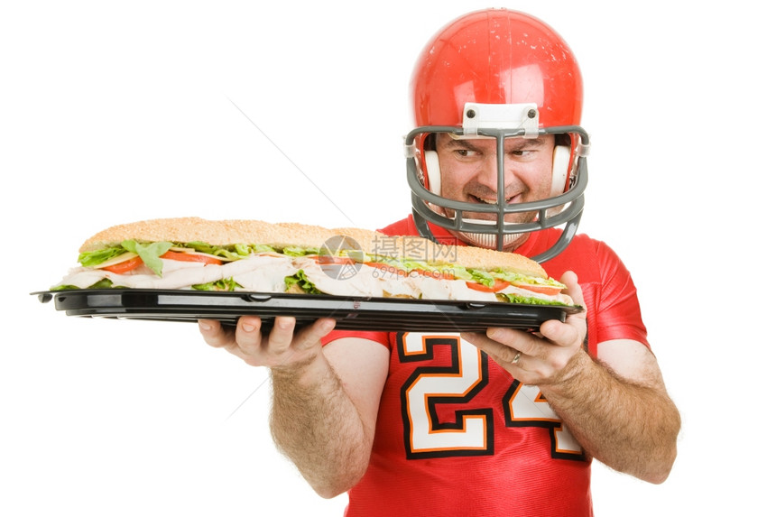 足球运动员满眼看着一个巨大的潜艇三明治孤立在白色上图片