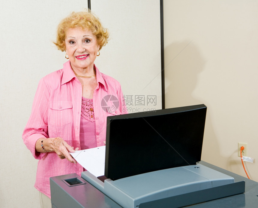 高级女将选票注入一个新的光学扫描投票机真实的图像拍摄给选举监督员图片