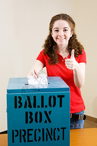 第一次投票的年轻选民投票并给予一个拇指举起的标志图片
