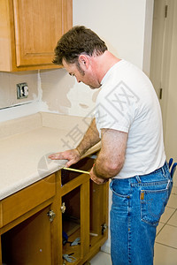 木匠改造厨房正在测量柜子集中注意力在男人身上图片