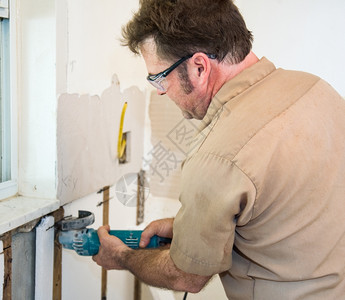 电工使用研磨机切割墙上的隔热层按照行业守则和安全标准真实和确地描述内容背景图片
