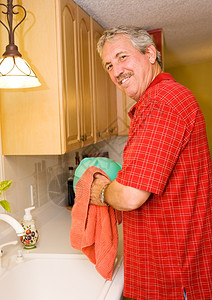 英俊的中年男子通过洗碗来帮忙图片