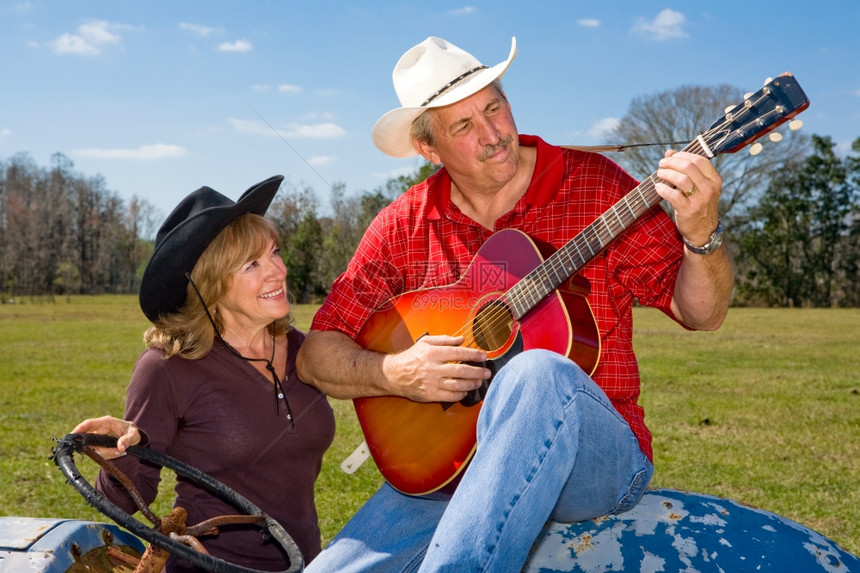 英俊的成熟签名牛仔弹吉他和精美的妻子图片