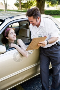 驾驶教练向青少年驾驶员展示她的考试结果图片