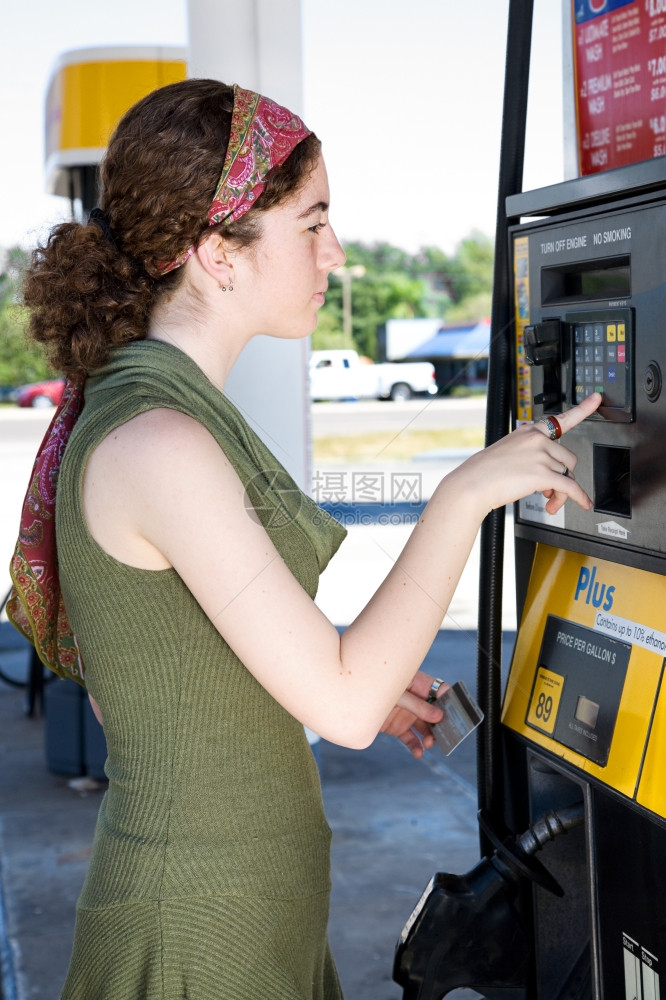 年轻妇女用她的自动取款机卡支付汽油费用图片