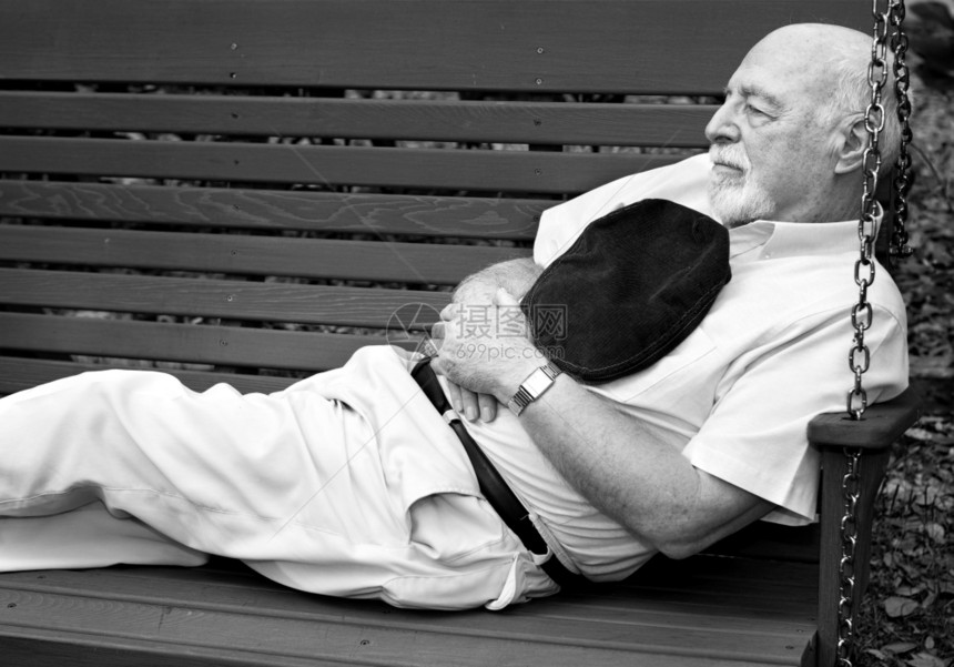 黑色和白的画面老人睡午觉在公园的秋千图片