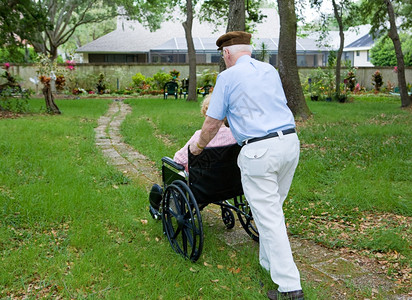 老人将残疾妻子推到轮椅上的花园里图片