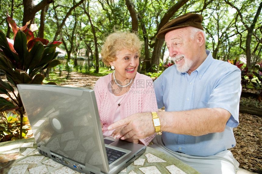 年长夫妇在笔记本电脑上在美丽的自然环境中图片