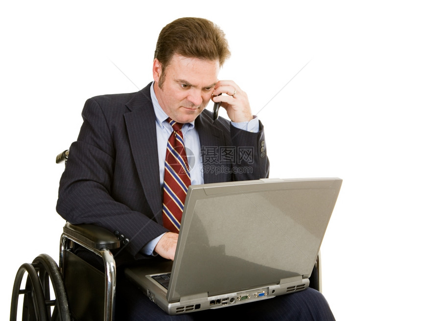 坐在轮椅上的成熟商人使用笔记本电脑和在话上说图片