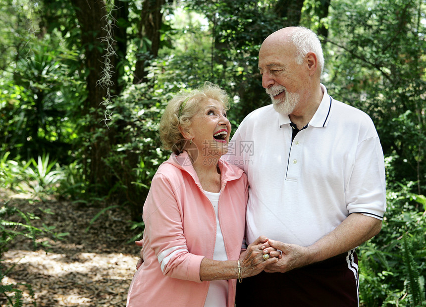 一个快乐活跃的老年夫妇在公园散步时一起大笑她戴着助听器有很多复制空间图片