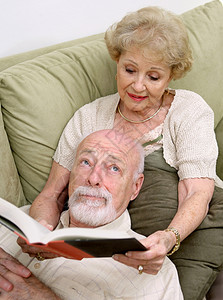 一位年长的女人向丈夫念书她正在无聊地翻来覆去图片