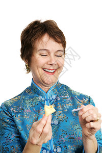 一个漂亮成熟的女人穿着丝绸的衬衫开一个幸运饼干并嘲笑里面的财富图片