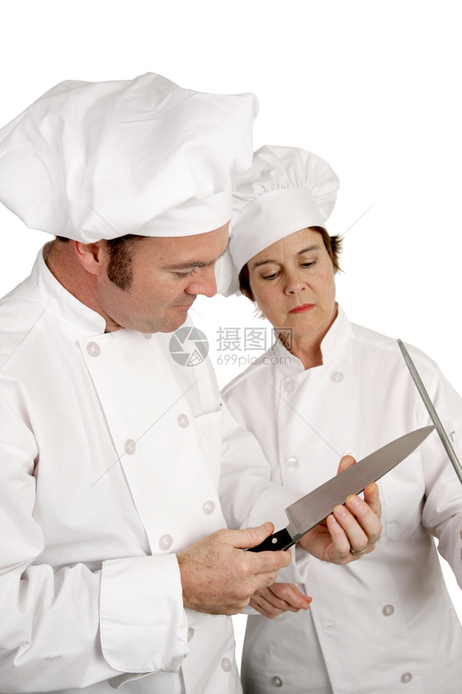 一位厨师在同事看时测试刀刃的锋利专注于男厨师图片
