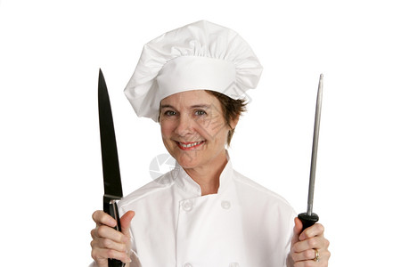 一个漂亮的厨师拿着一把大刀和磨白着被孤立图片