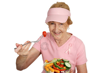 一位身穿粉红色乳癌意识丝带的老年妇女吃健康的沙拉被孤立在白色上图片