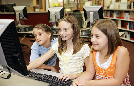 一群在校儿童学媒体中心电脑上工作玩得很开心图片