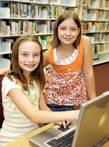 一个自信的年轻女学生帮助她的朋友做图书馆研究背景图片