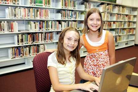 两个可爱的女学生在校图书馆做研究图片