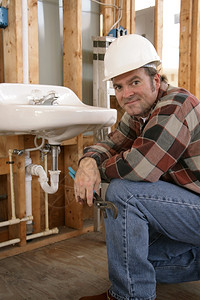 在建筑工地安装浴室置的友好水管工图片