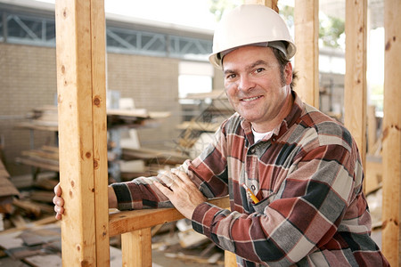 一个友善的微笑着建筑工人在作真正的建筑工人在实际的建筑工地图片