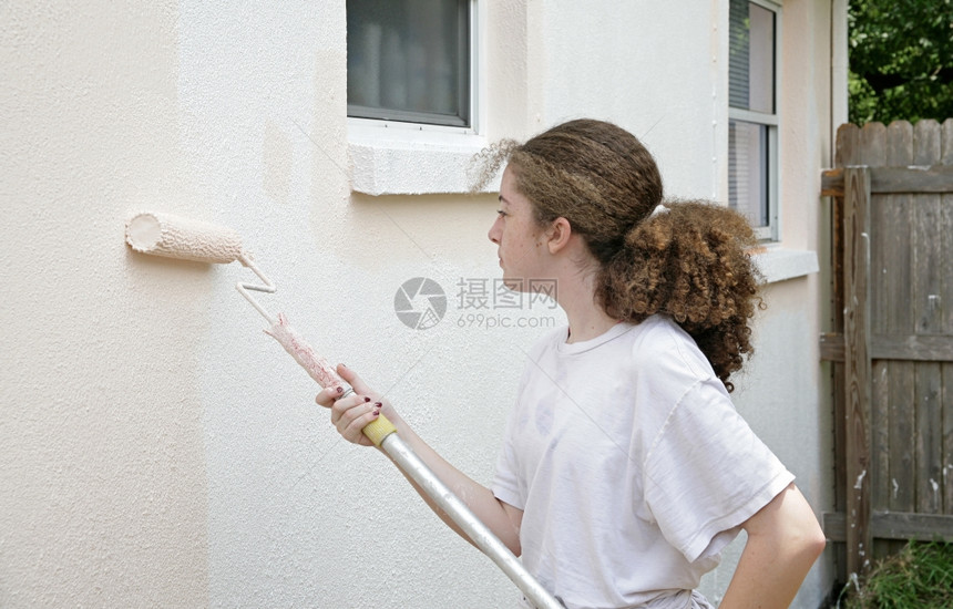 一个十几岁的女孩在她家侧面滚动着油漆水平视野图片