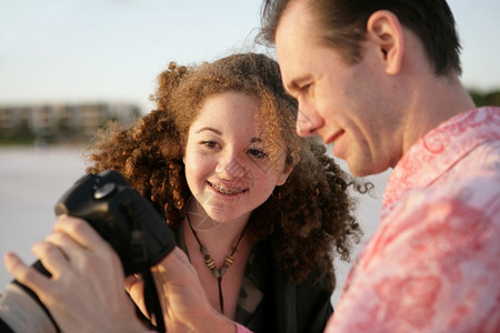 摄影师将照片展示给朋友看关注的是女孩和她反应深夜阳光温暖图片