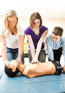 两个十几岁的女孩和一个男在学校练习心肺复苏术救生图片