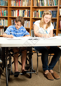 残疾男孩和一个朋友在学校图书馆做功课图片