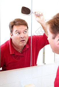 四十多岁的成熟男人用镜子检查头发上的秃斑图片