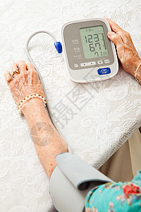 老年妇女使用自动血压监测家中的健康图片