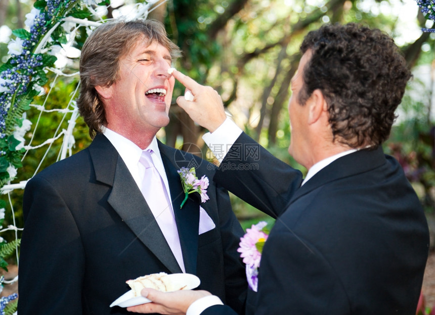 一位新郎在婚礼上将蛋糕贴在他丈夫的鼻子上图片