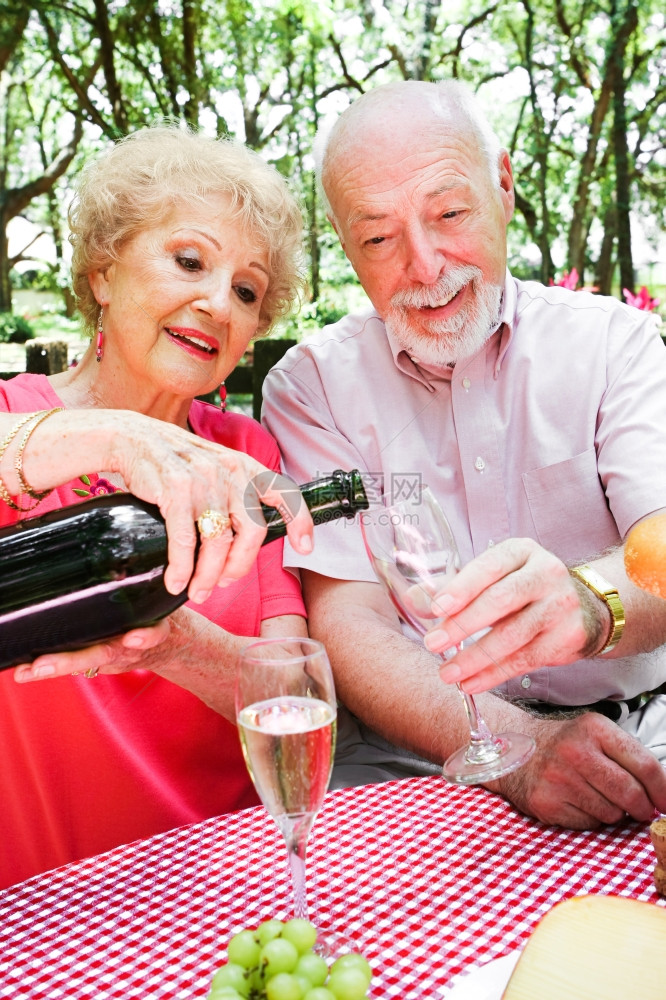 年长夫妇在浪漫野餐上妻子在倒香槟图片
