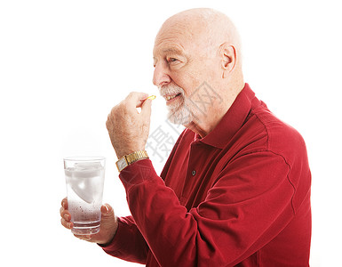 英俊的老年男子通过用一杯水补充鱼油保持健康图片