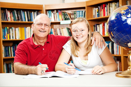 父亲和女儿在图书馆他帮助她做家庭作业图片