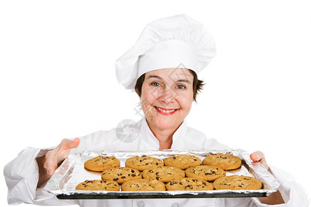 穿着制服的可爱女厨师拿着一盘美味的新鲜烤巧克力饼干图片
