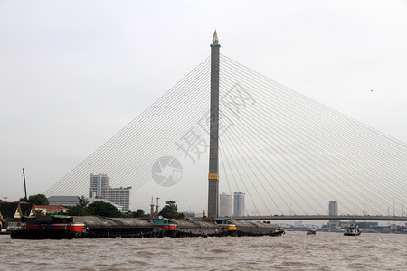 泰国曼谷ChaoPhraya河上的新桥和货船图片