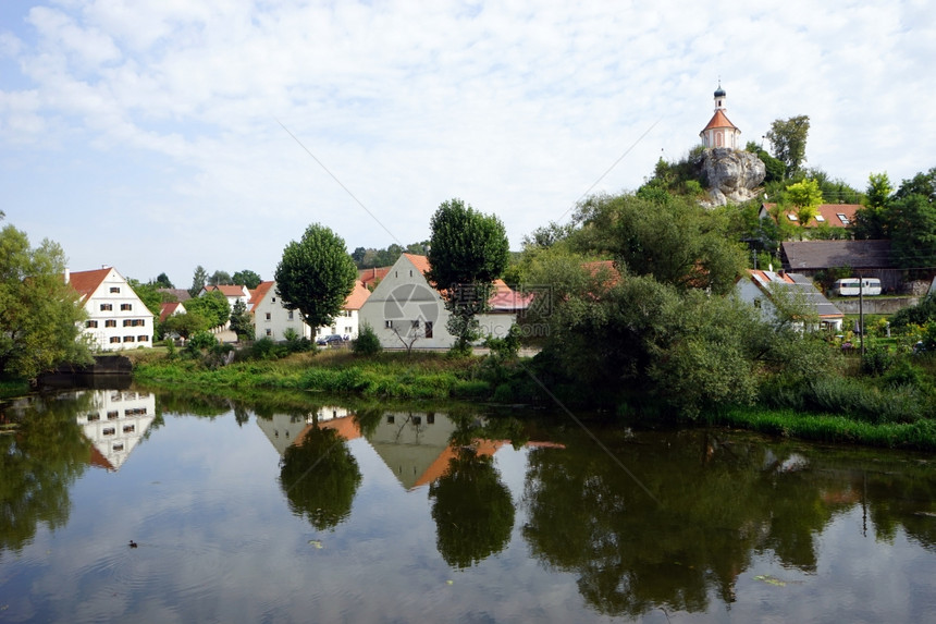 德国沃尼茨坦2015年9月1日河边的老房子和大树以及岩石上的小教堂图片